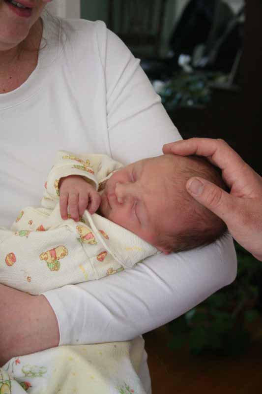 Alastair held by mom and touched by dad, on arrival home